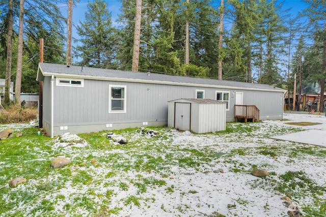 snow covered back of property featuring a storage shed