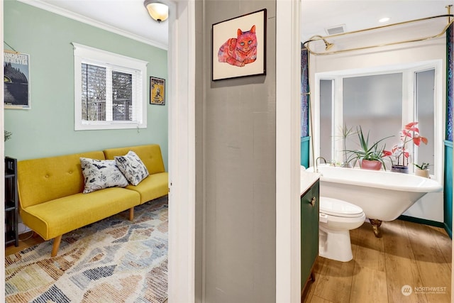 bathroom featuring a tub to relax in, hardwood / wood-style flooring, vanity, toilet, and crown molding