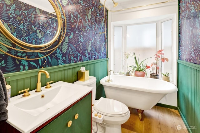 bathroom with wood-type flooring, toilet, vanity, and a washtub