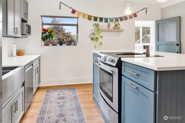 kitchen with pendant lighting, stainless steel appliances, light hardwood / wood-style flooring, and backsplash