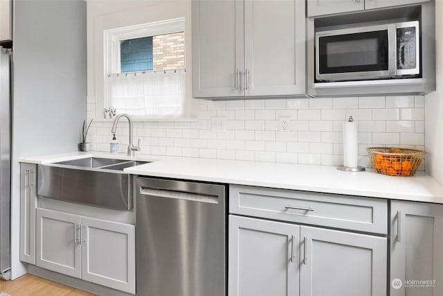 kitchen featuring backsplash, appliances with stainless steel finishes, sink, and gray cabinetry