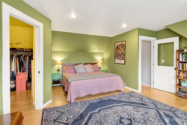 bedroom with lofted ceiling, a spacious closet, light wood-type flooring, and a closet