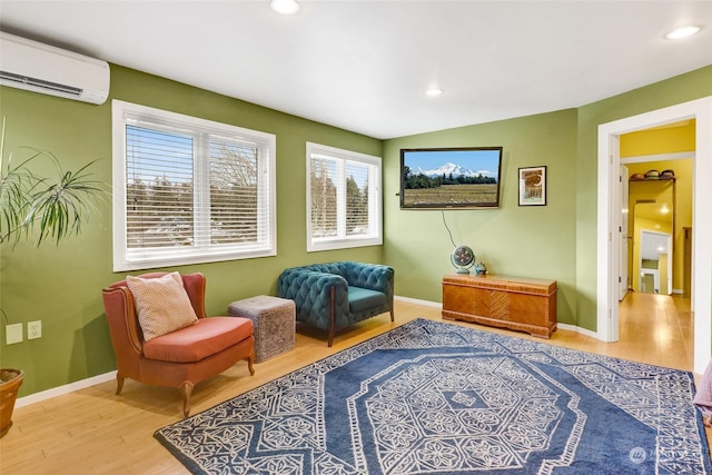 sitting room with hardwood / wood-style floors, vaulted ceiling, and a wall unit AC