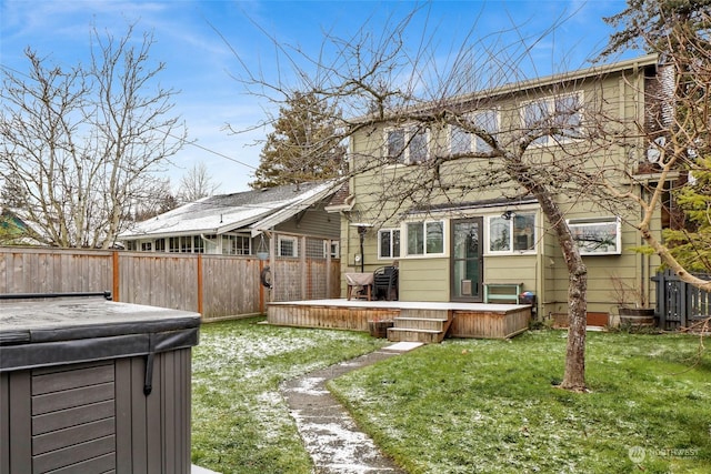 back of property with a hot tub, a deck, and a lawn