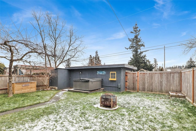 rear view of house with an outdoor fire pit and a hot tub