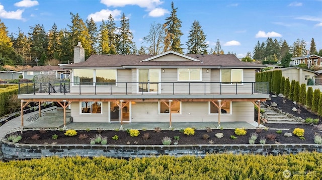 rear view of house with a wooden deck and a patio