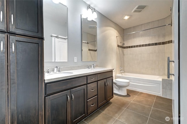 full bathroom with tiled shower / bath combo, vanity, tile patterned floors, and toilet