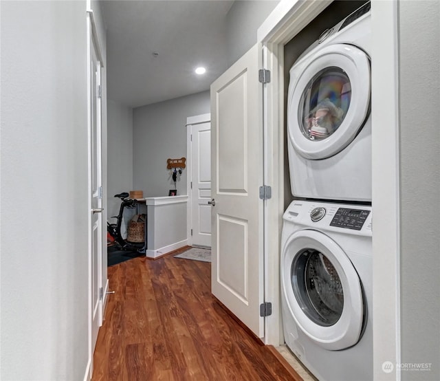 laundry room featuring stacked washer / dryer and dark hardwood / wood-style flooring