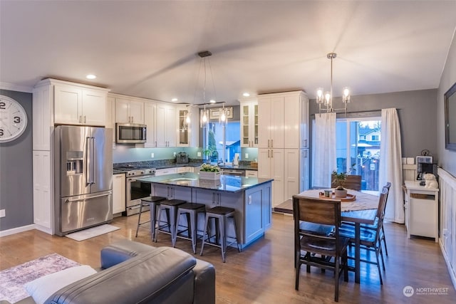 kitchen featuring white cabinetry, a breakfast bar, hanging light fixtures, and premium appliances