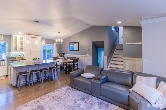 living room featuring lofted ceiling, wood-type flooring, and an inviting chandelier