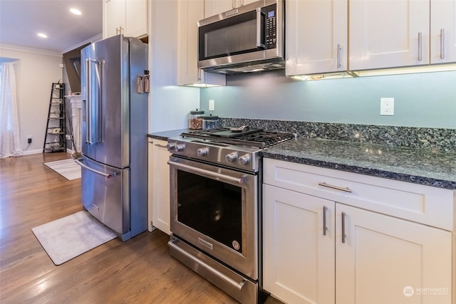 kitchen featuring stainless steel appliances, white cabinetry, dark hardwood / wood-style floors, and crown molding