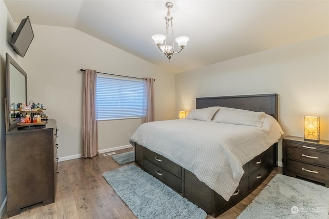 bedroom with an inviting chandelier, lofted ceiling, and light hardwood / wood-style floors