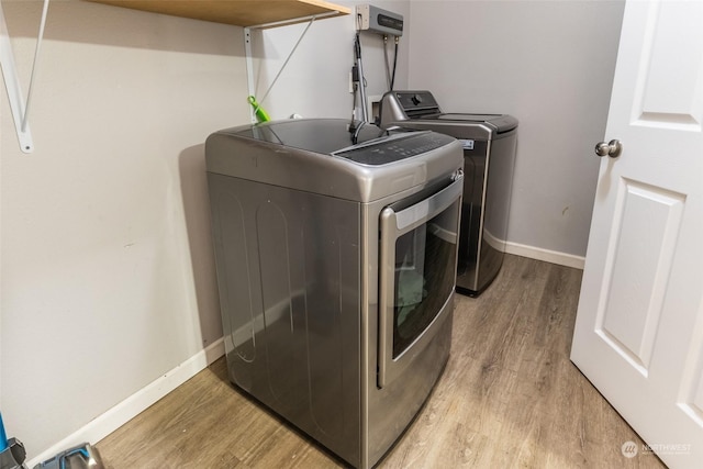 laundry area featuring separate washer and dryer and light hardwood / wood-style flooring