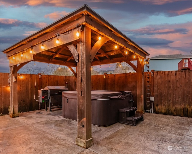 patio terrace at dusk featuring a hot tub and a gazebo