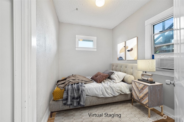 bedroom featuring cooling unit, a textured ceiling, and light wood-type flooring