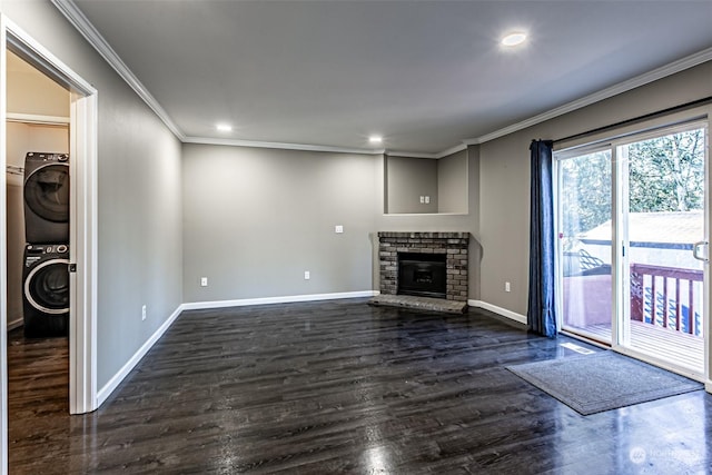 unfurnished living room with crown molding, stacked washer and clothes dryer, dark hardwood / wood-style flooring, and a brick fireplace