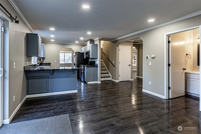 kitchen with dark hardwood / wood-style floors, a kitchen breakfast bar, ornamental molding, kitchen peninsula, and stainless steel range oven