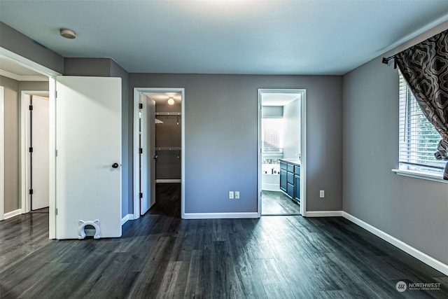 unfurnished bedroom featuring connected bathroom, dark hardwood / wood-style floors, a closet, and a spacious closet