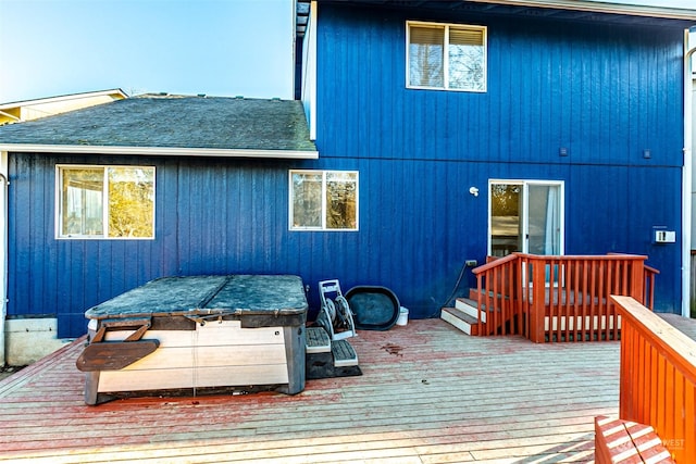 rear view of property featuring a hot tub and a deck