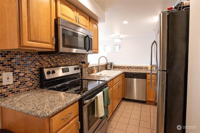 kitchen featuring light stone counters, sink, light tile patterned flooring, and appliances with stainless steel finishes