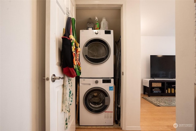 laundry area with stacked washer / drying machine and hardwood / wood-style floors