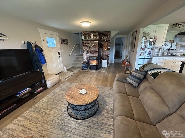 living room with sink, wood-type flooring, and a wood stove