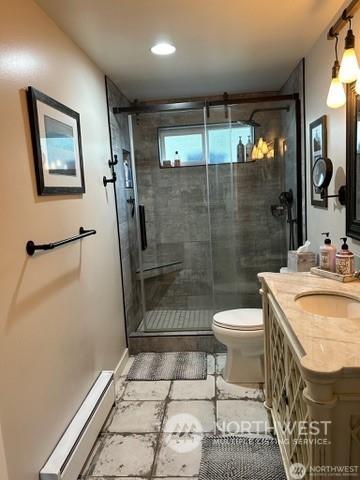 bathroom with a baseboard radiator, vanity, toilet, and an enclosed shower