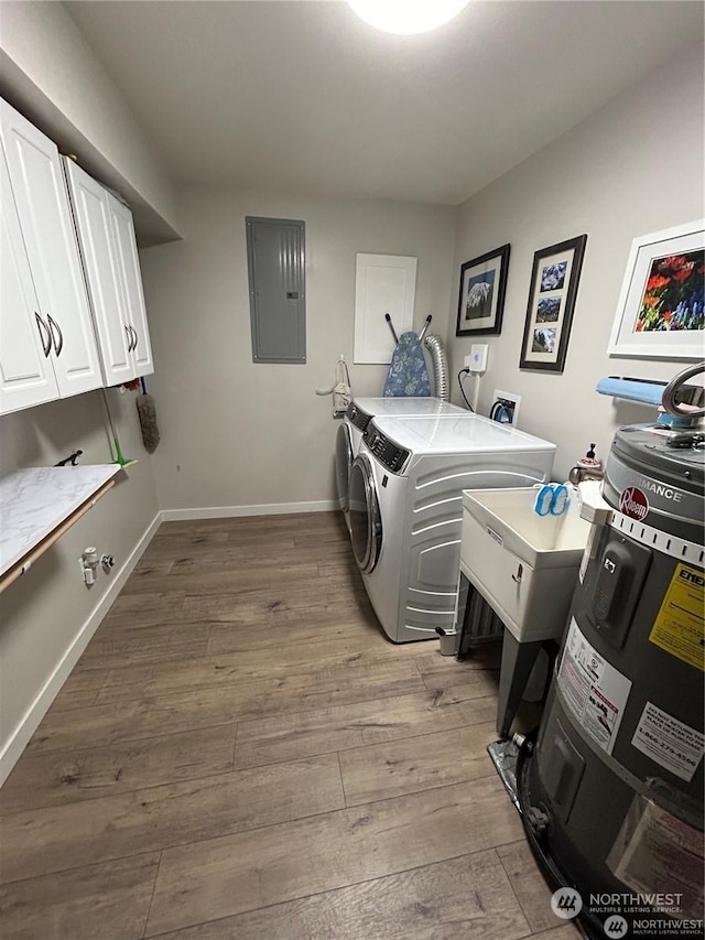 clothes washing area featuring light hardwood / wood-style flooring, electric panel, cabinets, and washing machine and clothes dryer