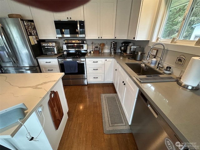 kitchen featuring white cabinetry, appliances with stainless steel finishes, light stone countertops, and sink