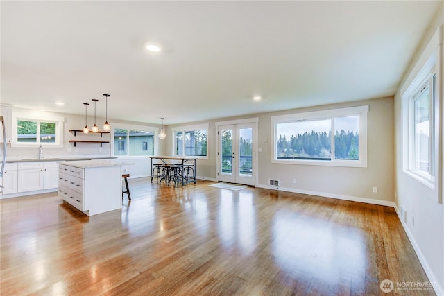 kitchen featuring a sink, visible vents, a kitchen breakfast bar, french doors, and a center island