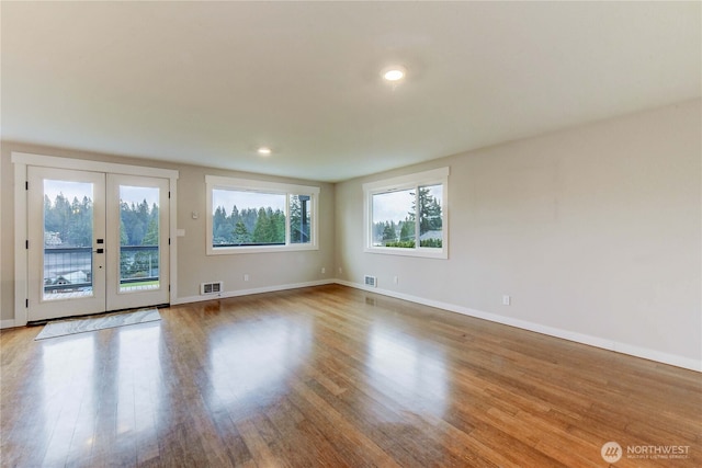 empty room with baseboards, visible vents, and wood finished floors