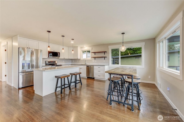 kitchen with stainless steel appliances, dark wood-type flooring, a kitchen island, white cabinetry, and open shelves