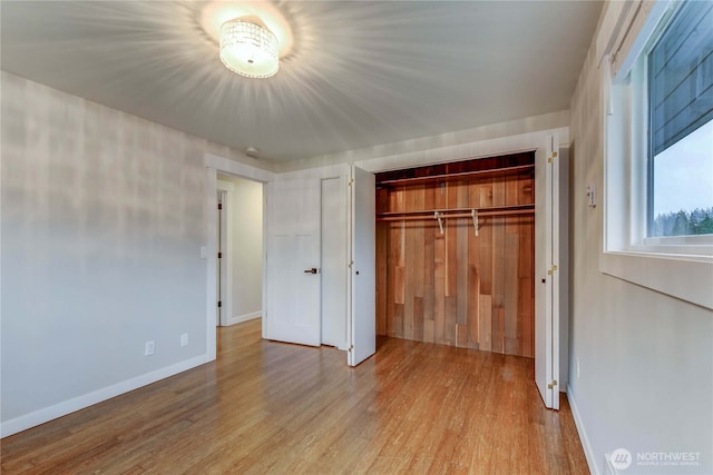 unfurnished bedroom featuring a closet, wood finished floors, and baseboards