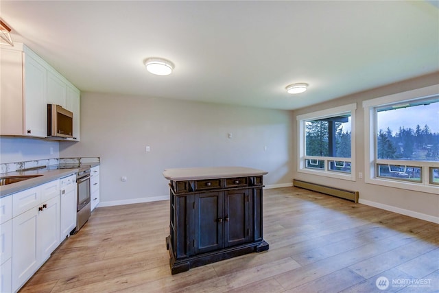 kitchen with a baseboard radiator, light wood-style flooring, and white cabinetry