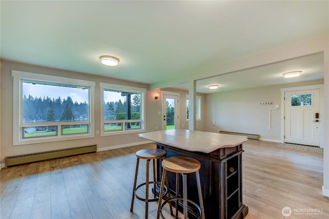 kitchen with baseboard heating, a baseboard heating unit, a kitchen island, light wood-type flooring, and baseboards