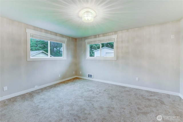 carpeted spare room with visible vents and baseboards