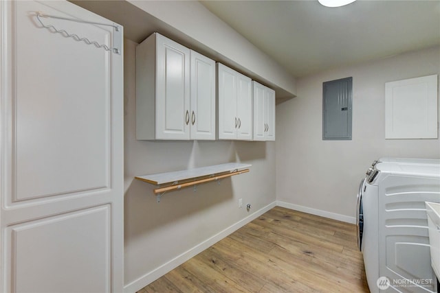 washroom with cabinet space, electric panel, baseboards, light wood-style flooring, and washing machine and clothes dryer