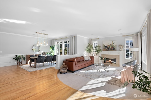 living room with light hardwood / wood-style flooring, ornamental molding, and a healthy amount of sunlight