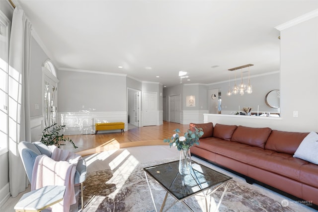 living room with crown molding, an inviting chandelier, and light hardwood / wood-style floors