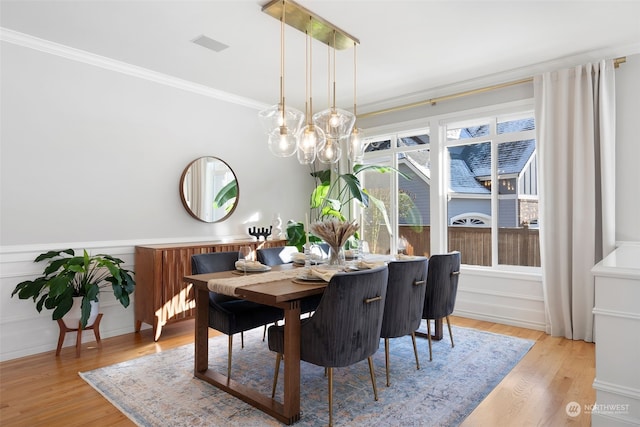 dining space with ornamental molding and light hardwood / wood-style floors