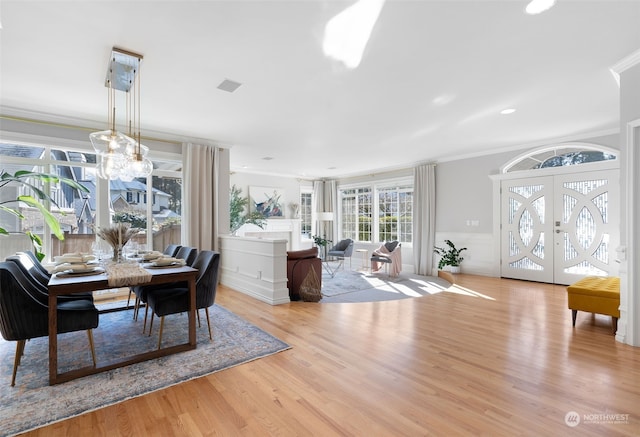 dining room featuring french doors, a notable chandelier, crown molding, and light wood-type flooring