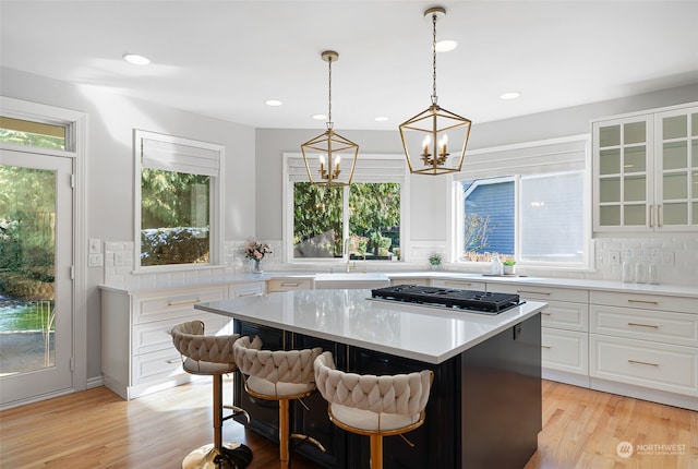 kitchen featuring a kitchen bar, a center island, sink, and white cabinets