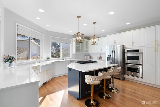 kitchen featuring a breakfast bar area, decorative light fixtures, appliances with stainless steel finishes, a kitchen island, and white cabinets