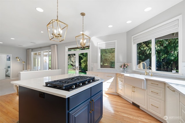 kitchen with blue cabinets, sink, a center island, black gas stovetop, and french doors