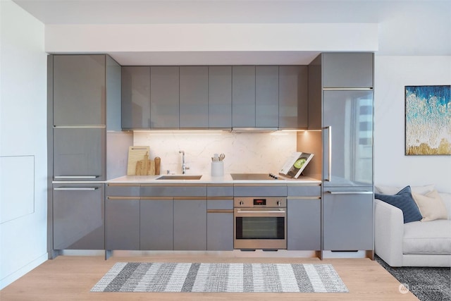 kitchen featuring tasteful backsplash, sink, gray cabinets, and oven