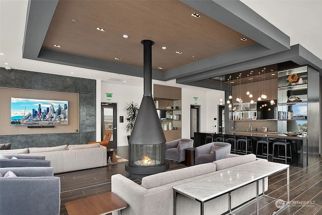 living room with a wood stove, bar area, and a tray ceiling