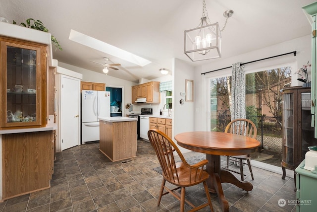 dining area with lofted ceiling with skylight, sink, and a notable chandelier