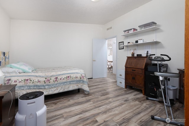 bedroom with light hardwood / wood-style floors and a textured ceiling