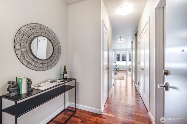 corridor featuring dark wood finished floors and baseboards