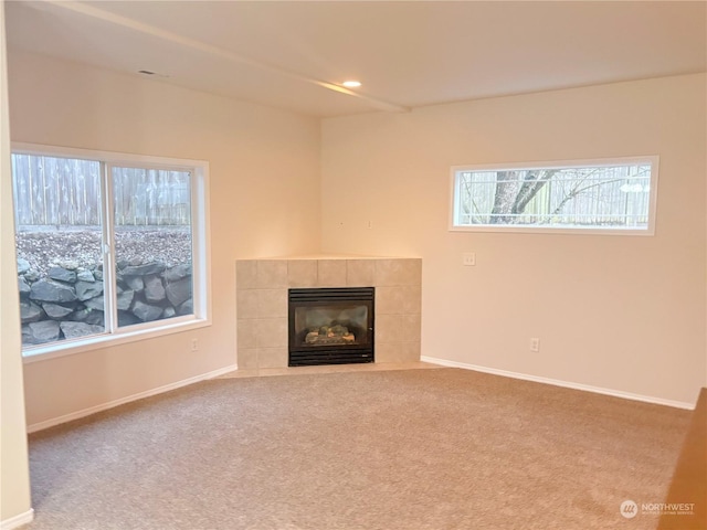 unfurnished living room featuring a tiled fireplace and carpet floors